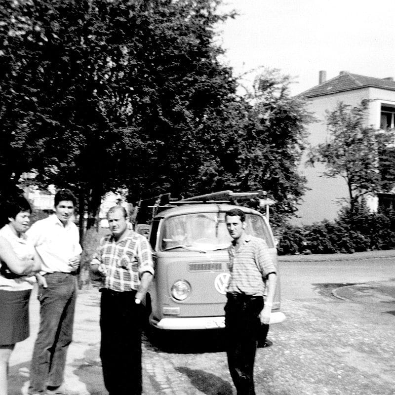 Schwarzweißaufnahme von vier Personen vor dem ersten VW Pritschenwagen der Firma Dachdecker Otto.