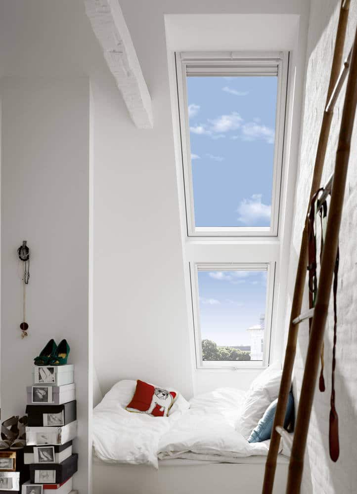 Zwei Dachfenster übereinander erhellen ein weißes Schlafzimmer.