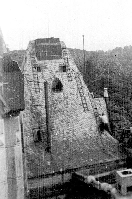 Schwarzweißaufnahme von Dachdeckern beim anbringen von Schiefer auf der Dachfläche der Kommende Ramersdorf in Bonn.