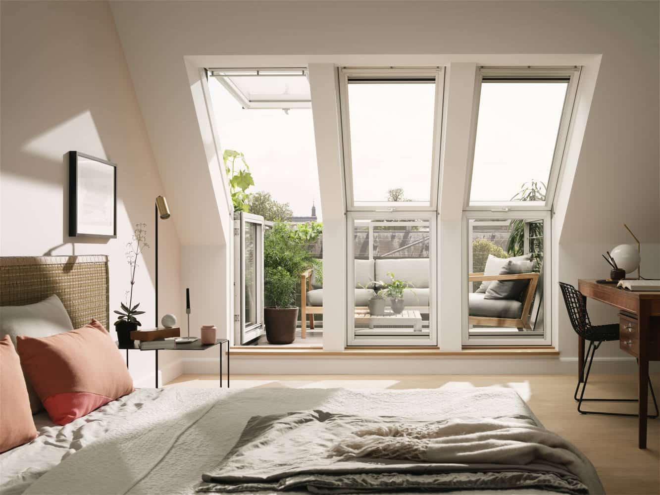 Ein sehr helles Schlafzimmer unter dem Dach mit einer Terrasse und großen Dachfenstern.