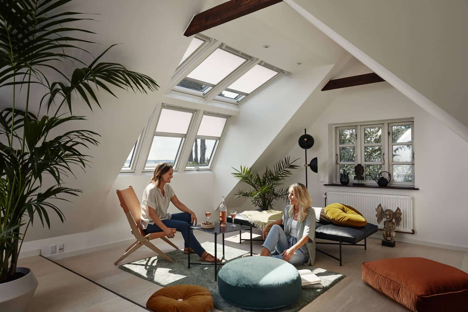 Zwei Faruen in einem hellen Wohnzimmer eines Dachboden, der mit Dachfenstern ausgestattet wurde.