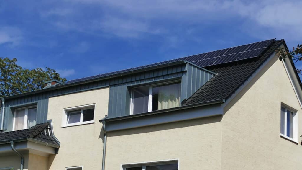 Das neu eingedeckte Dach, mit zinkverkleidetem Ausbau und Solaranlage, eines Mehrfamilienhaus in Bonn.