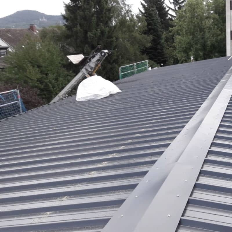 Verarbeitung von Strahltrapezblech auf dem Dach eines Schulgebäudes.